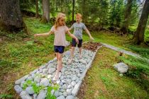 Kleine wie große Wanderer erspüren die Erde auf dem Barfußweg des neuen "Vitalweg Holzgau" im Tiroler Lechtal. • © Lechtal Tourismus